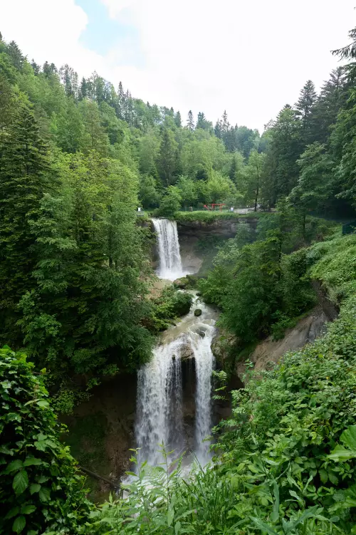 Scheidegger Wasserfälle, umrahmt von grünen Bäumen, die sonst eher ein Rinnsal bieten, sind durch regenreiche Tage zu einem imposanten Wasserfall angewachsen.