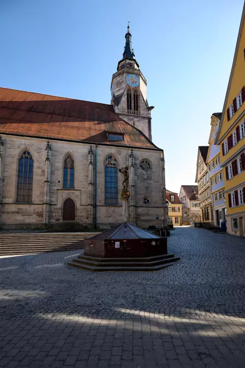 Blick auf die St. Georg Figur, auf dem abgedeckten Brunnen, vor der im Hintergund zu sehenden Stiftskirche in Tübingen.