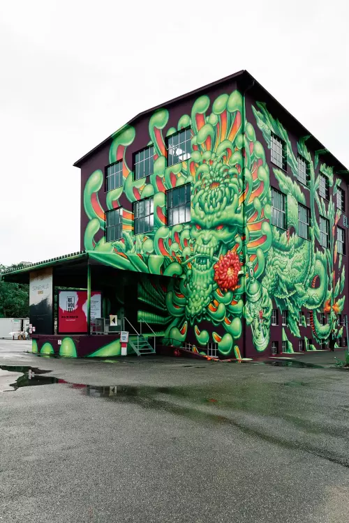 Das giftgrüne, orangefarbene Graffito eines Phantasiewesens geht vom Boden bis unter das Dach der circa 20 Meter hohen Schwelhalle Balingen.