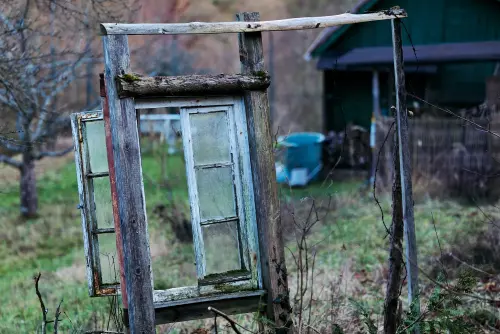 Marode Rankhilfe, bestehend aus Pfosten, Latten und einem alten Fensterahmen