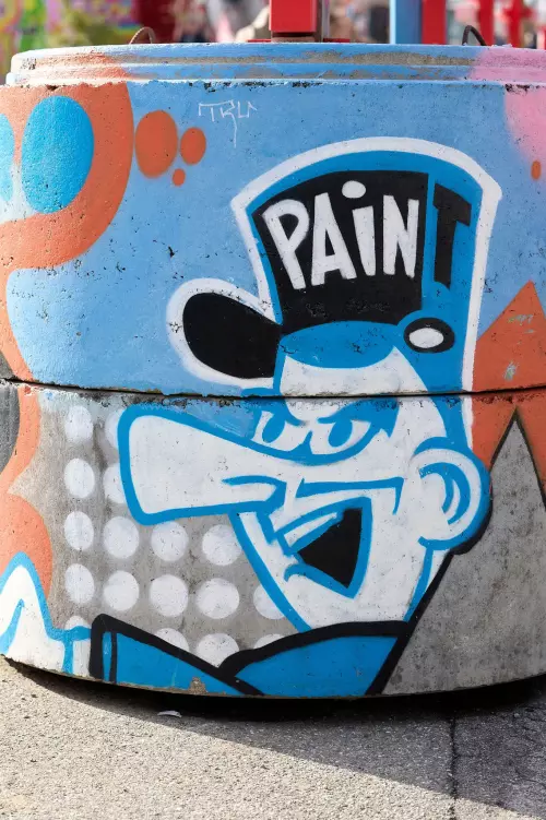 Graffiti auf Betonsäulen, das einen Polizisten mit französisch aussehender Uniform aus den 1950-/60-er Jahren zeigt, auf dessen Mütze das Wort "PAIN T" zu lesen ist.