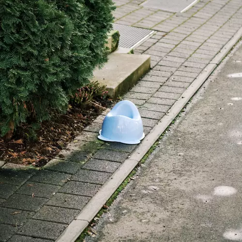 Ein hellblaues Töpfle oder Töpfchen aus Plastik, mitten auf dem Randstreifen eines Grundstücks an der Straße.