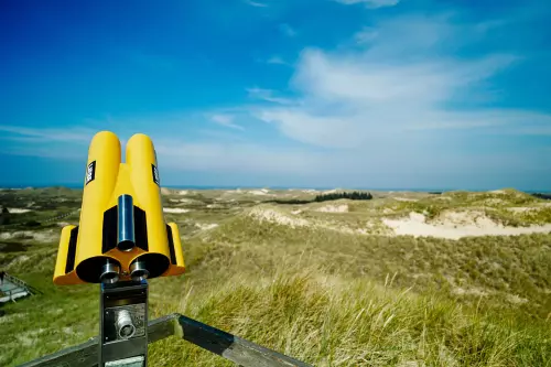 Aussichtsplattform im Spätsommer in den Dünen von Amrum mit einem gelb lackierten Fernrohr auf dem Etiketten mit dem Wort Liebe angebracht wurden.