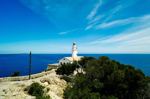 Der Leuchtturm, an einem sonnigen Tag vor dunkelblauem Meer und blauem Himmel, steht auf der Far de Capdepera an der Nordostküste von Mallorca.