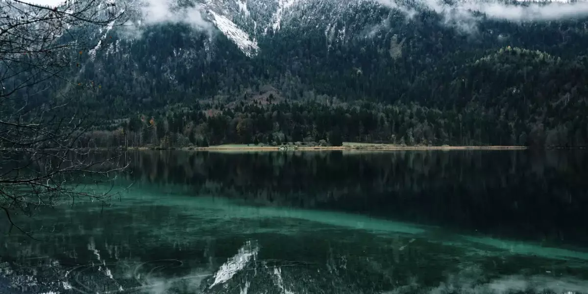 Glatte, blaugrünlich schimmernde Oberfläche vom Alpsee vor dem Berg Gassenthomaskopf