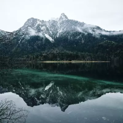 Glatte, blaugrünlich schimmernde Oberfläche vom Alpsee vor dem Berg Gassenthomaskopf