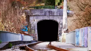 Froschperspektive mit Gleisen im Vordergrund, die in einen Eisenbahntunnel der Ammertalbahn in Tübingen führen.